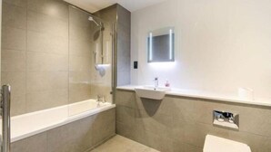 A modern bathroom with a bathtub, a sink, and a toilet. - Impeccable 1-bed Apartment in London (London)