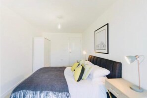 A bedroom with a bed, bedside table, lamp, and a framed picture on the wall. - Impeccable 1-bed Apartment in London (London)