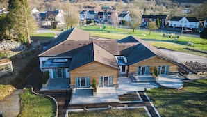 A modern two-story house with a sloped roof, a covered patio, and a landscaped front yard. - The Sleeping Giant - Pen Y Cae Inn (Swansea)