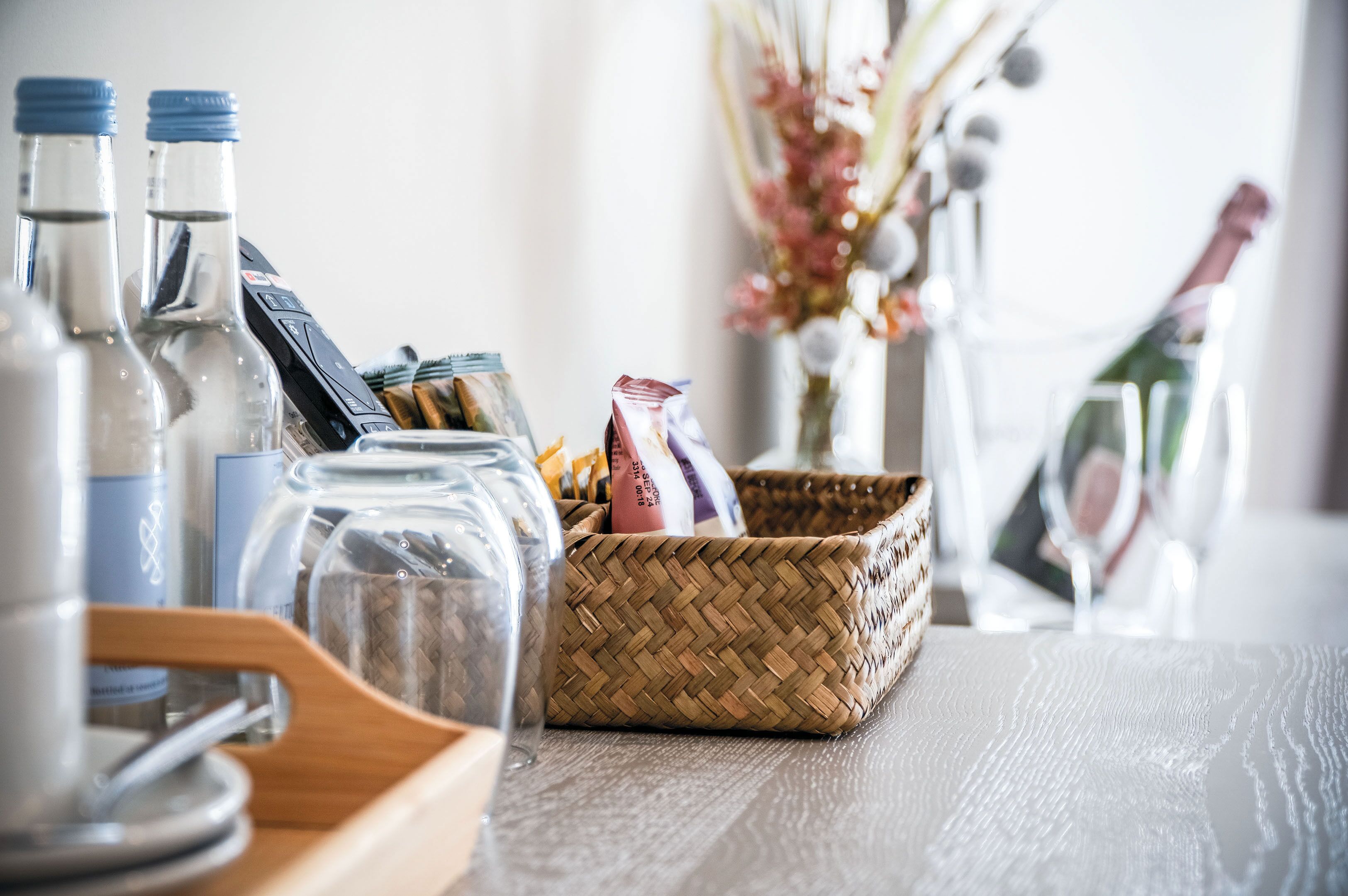 A table with glass bottles, a woven basket, and a glass.