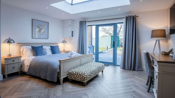 A bedroom with a skylight, a bed with pillows, a bench, a desk, and a chair. - The Sleeping Giant - Pen Y Cae Inn (Swansea)