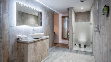 A modern bathroom with a wooden vanity, a large mirror, and a walk-in shower.