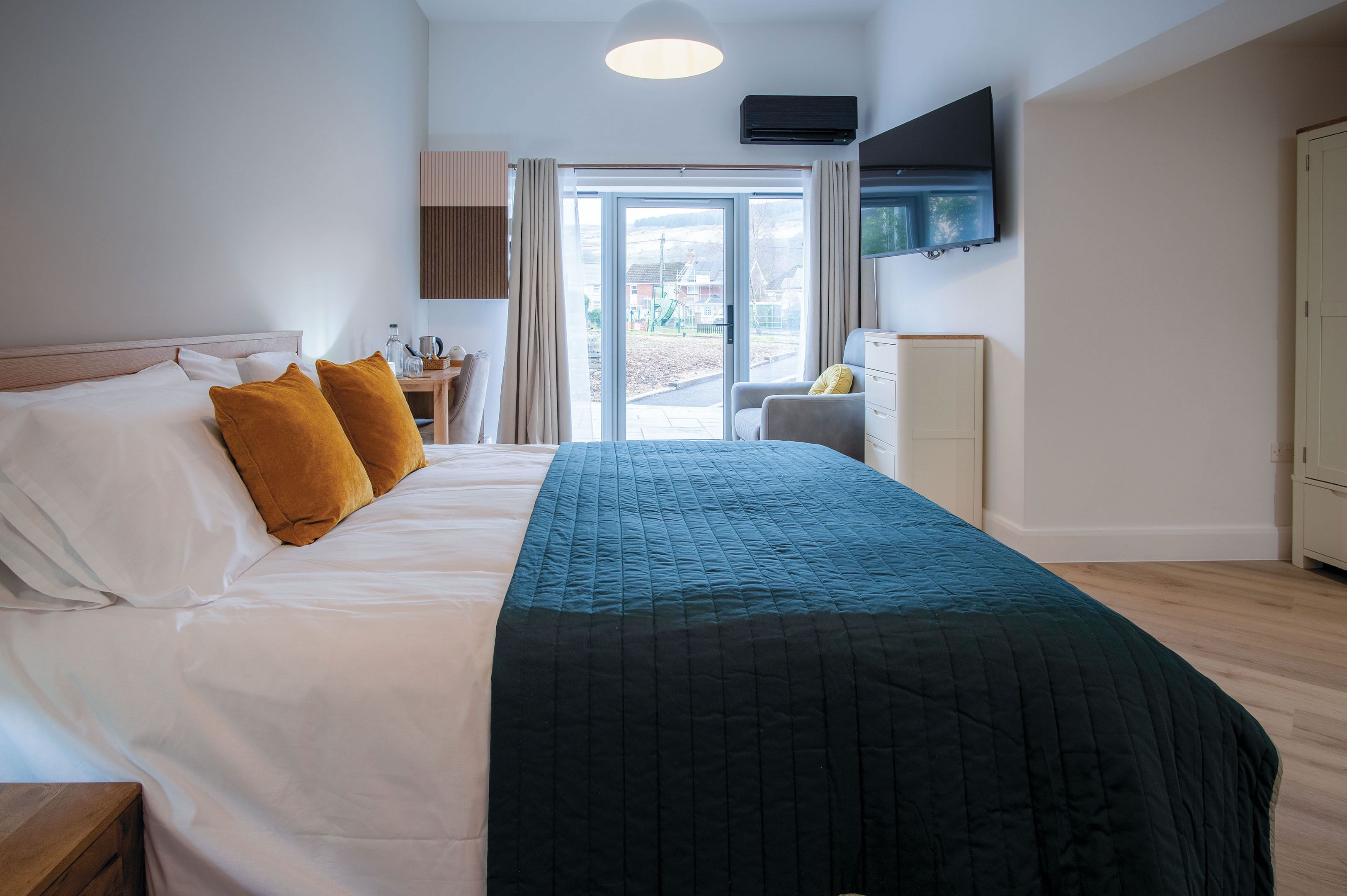 Habitación de hotel con cama, escritorio, silla y televisor en la pared.