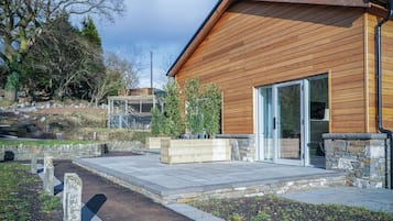 A modern building with wooden siding, a glass door entrance, and a stone foundation.