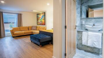 A modern living room with a sofa, ottoman, and a painting on the wall.
