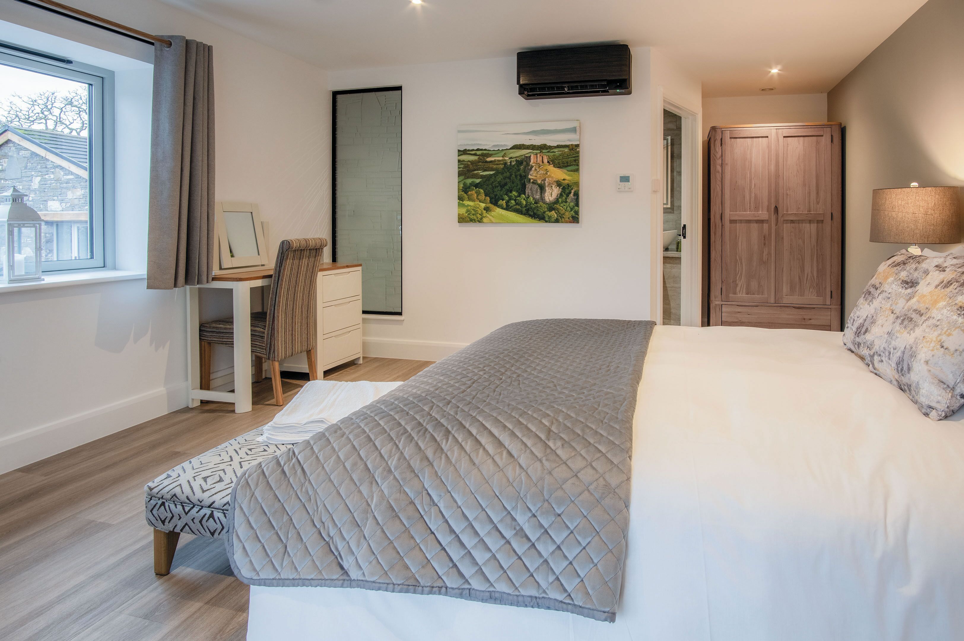 Une chambre à coucher comprenant un lit, un bureau, une chaise, une armoire et une fenêtre avec des rideaux.