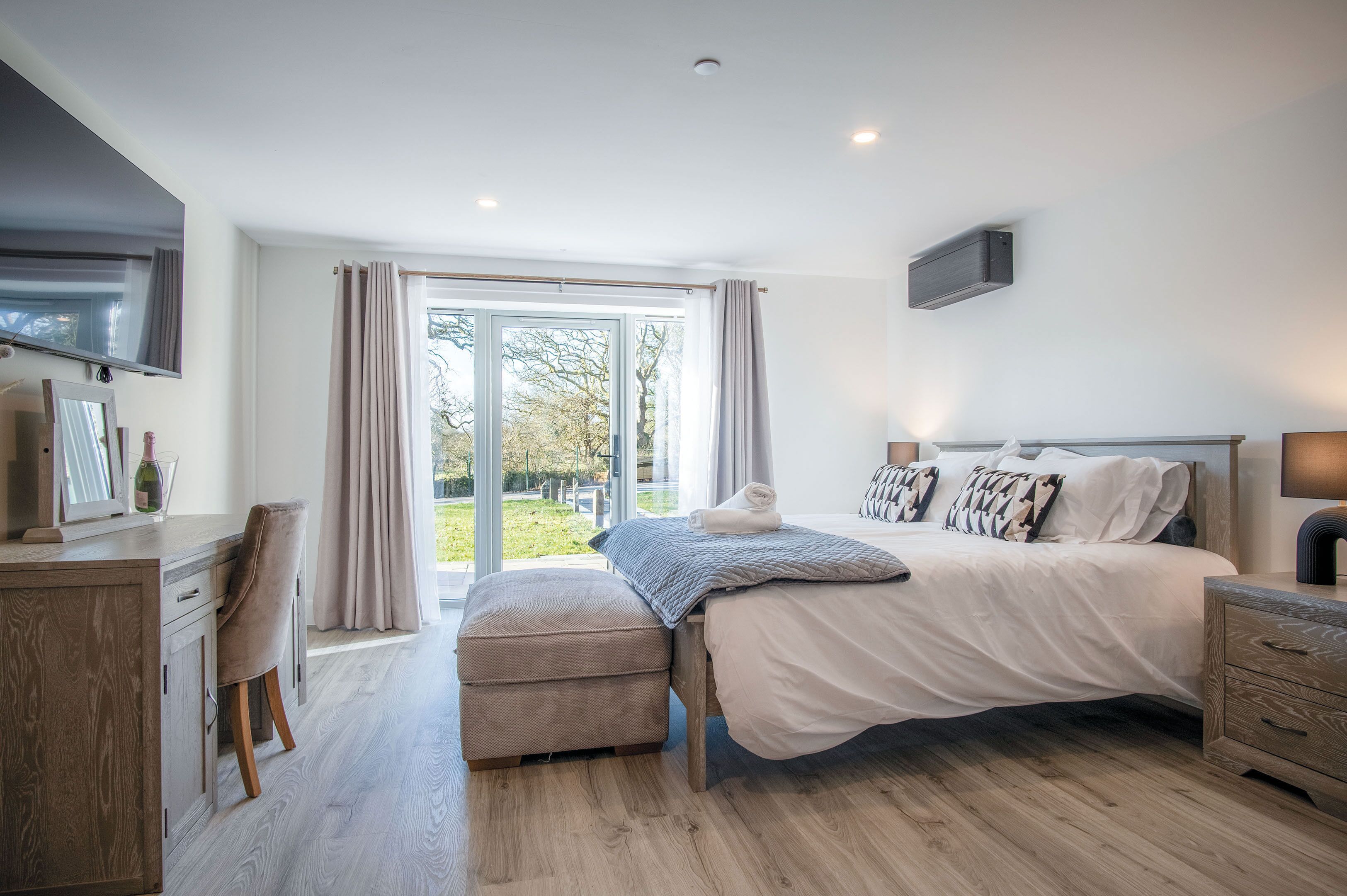 A modern bedroom with a large bed, a desk, and a chair.