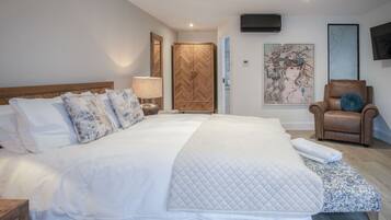 Een ruime slaapkamer met een groot bed, een houten kledingkast, een stoel en kunst aan de wanden.