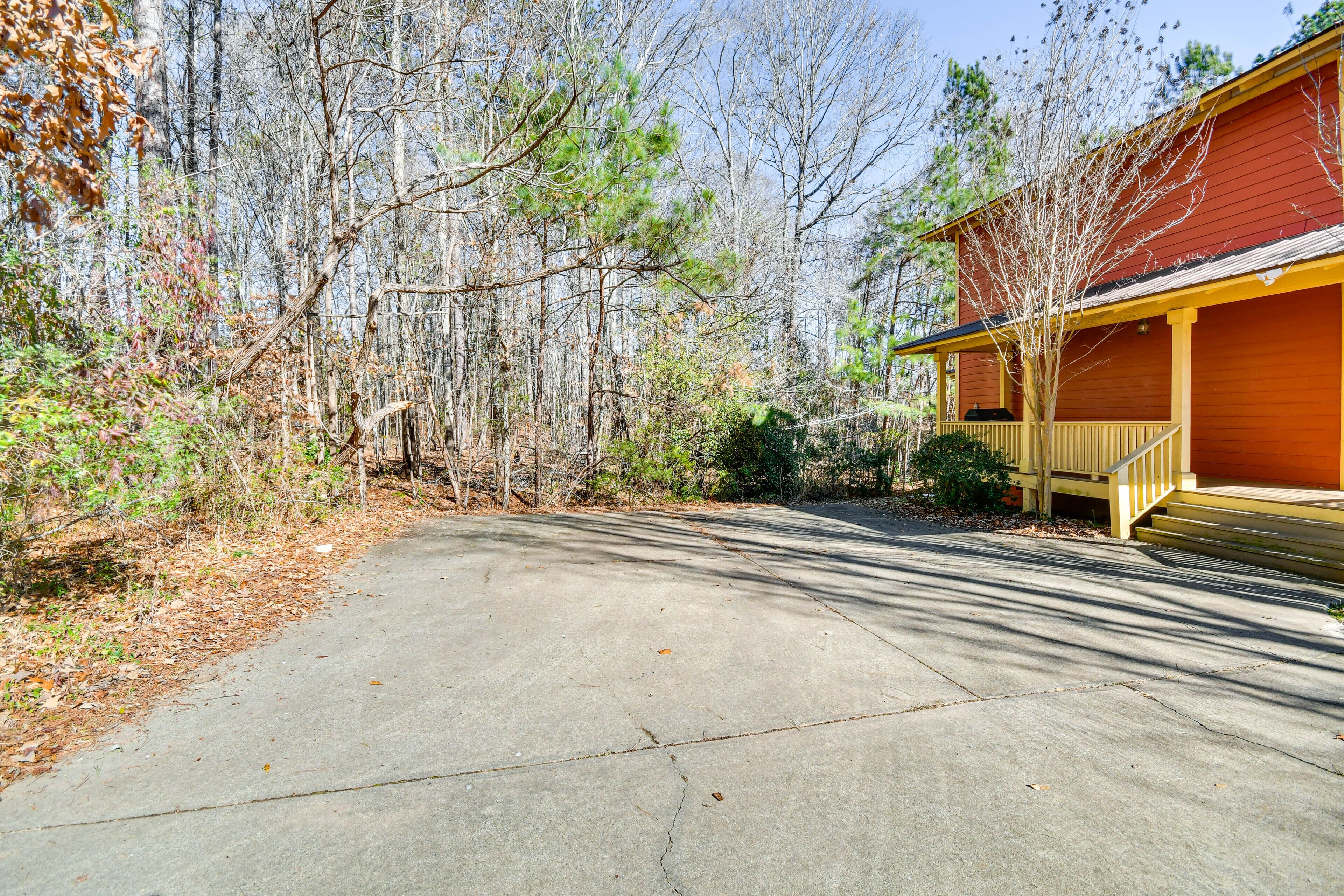 A concrete driveway leading to a red building with a yellow porch.
