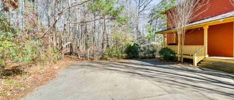 A concrete driveway leading to a red building with a yellow porch.