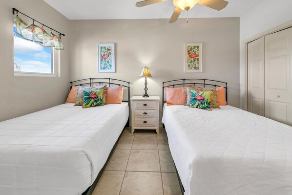 A bedroom with two beds, a nightstand, a lamp, and artwork on the walls. - 🌊Gulf Views, Pool, Great Location, 3BR, Sterling Reef 407 (Panama City Beach)