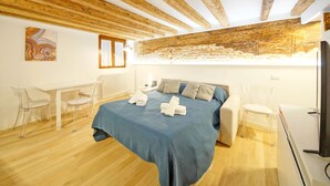 Een slaapkamer met een bed, een bureau en stoelen.
