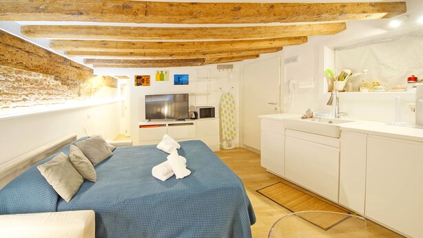 Een slaapkamer met een bed, een televisie, een magnetron en een kitchenette.
