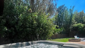 Un bain à remous entouré d’une végétation luxuriante et délimité par une clôture en bois.