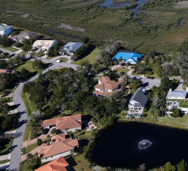 An aerial view of a residential area with houses, a large body of water, and a small island with a fountain. - Spacious Home Prime Location of St. Augustine: Pool, Hot Tub, & Fire Pit (St. Augustine)