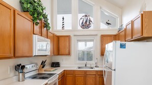 A kitchen with wooden cabinets, a microwave, a stove, a sink, and a refrigerator. - Carolyna Sun, Oceanfront Duplex in Emerald Isle, NC! (Emerald Isle)