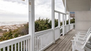 A covered wooden deck with white railings, overlooking a beach and ocean view. - Carolyna Sun, Oceanfront Duplex in Emerald Isle, NC! (Emerald Isle)