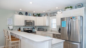 A modern kitchen with white cabinetry, stainless steel appliances, and a central island.