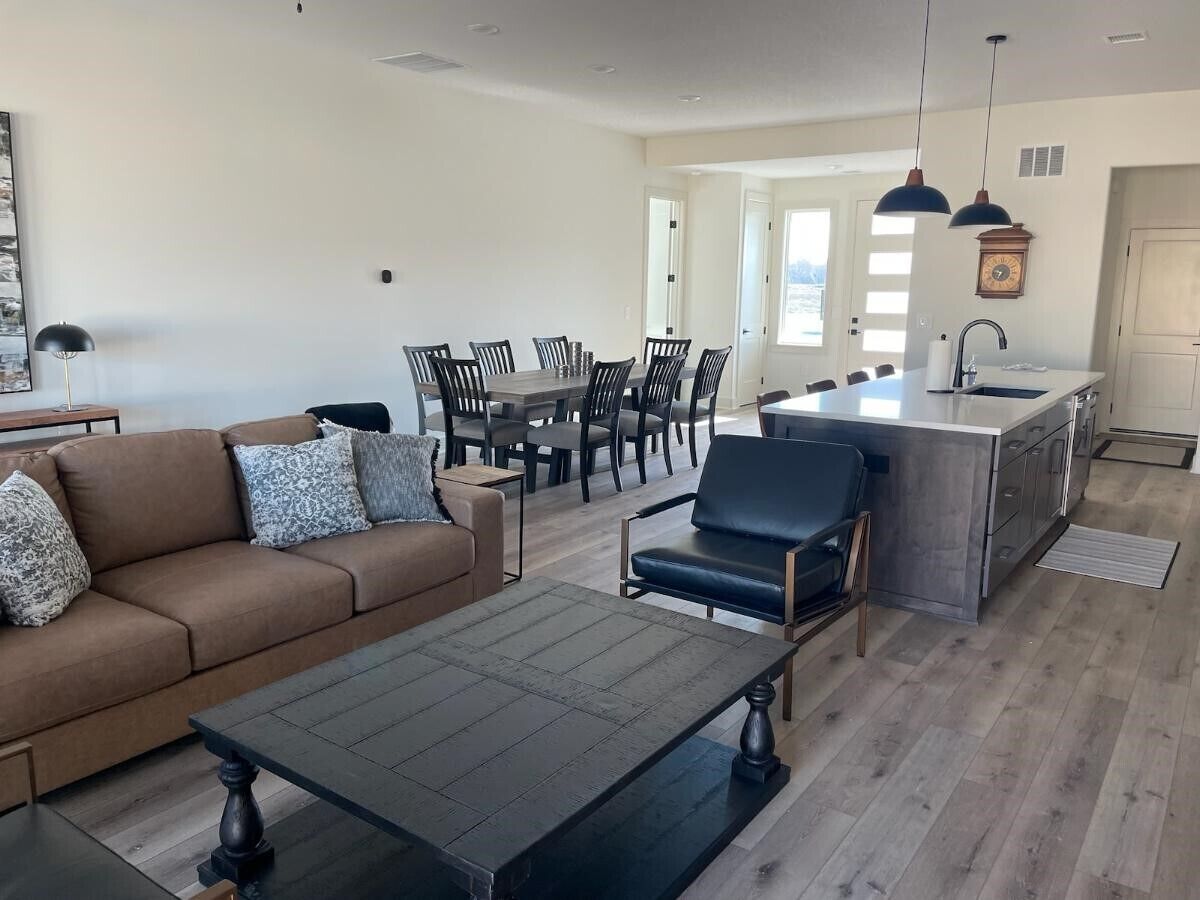 Ein modernes Wohnzimmer mit Sofa, Couchtisch und Essbereich mit Stühlen.