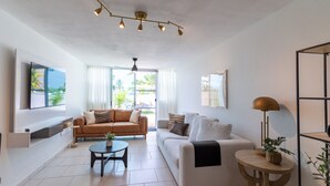 Una sala de estar moderna con un sofá, una mesa de centro y un televisor montado en la pared.