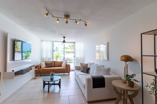 A modern living room with a sofa, coffee table, and a TV mounted on the wall.