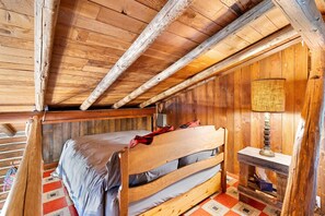 Une chambre dans une cabane en bois, avec un lit, une lampe et un sol à carreaux.