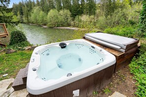 Un bain à remous situé dans un espace boisé, avec une rivière en arrière-plan.
