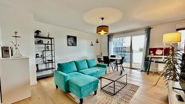 Uma sala de estar moderna com um sofá verde-água, uma área de jantar e uma varanda com vista.