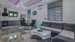 Un salon moderne avec un canapé gris, une table basse blanche et un coin repas comprenant une table et des chaises.