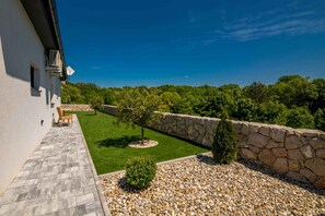 A modern building with a stone wall, a paved patio, and a well-maintained lawn.