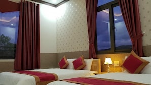 Ein Hotelzimmer mit zwei Betten, roten Vorhängen, Blick auf den Nachthimmel und einer Wand mit Muster.