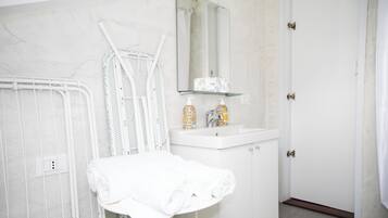 Un baño con lavamanos blanco, un espejo y un perchero para toallas.
