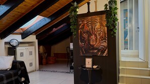 Ein Zimmer mit hohen Decken, einem schwarz-weißen Sofabezug, einem kleinen Tisch mit einem dekorativen Gegenstand und einem Tigergemälde an der Wand.
