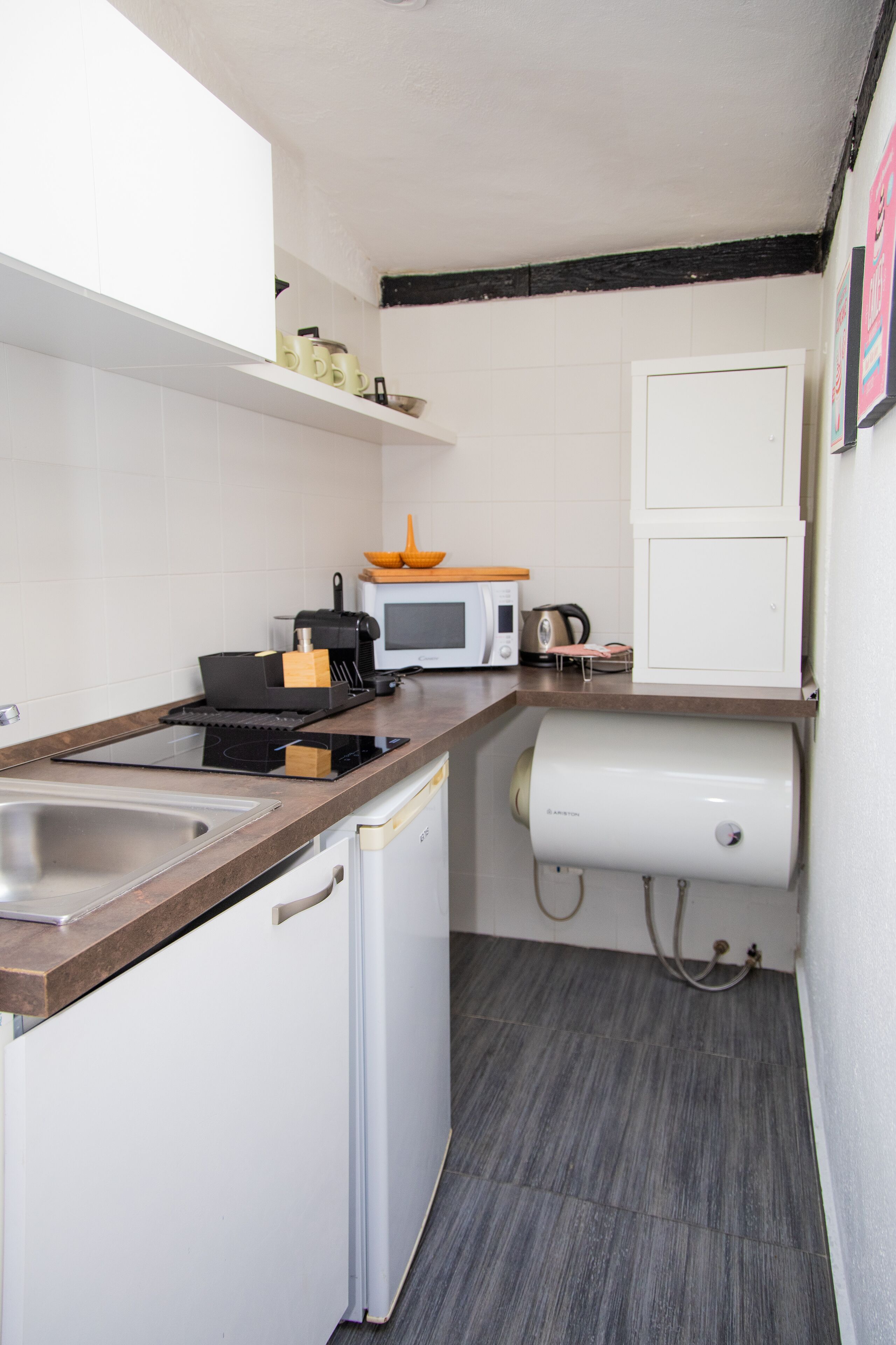 Une cuisine de taille réduite équipée d’un évier, d’une cuisinière, d’un four à micro-ondes et d’un petit réfrigérateur.