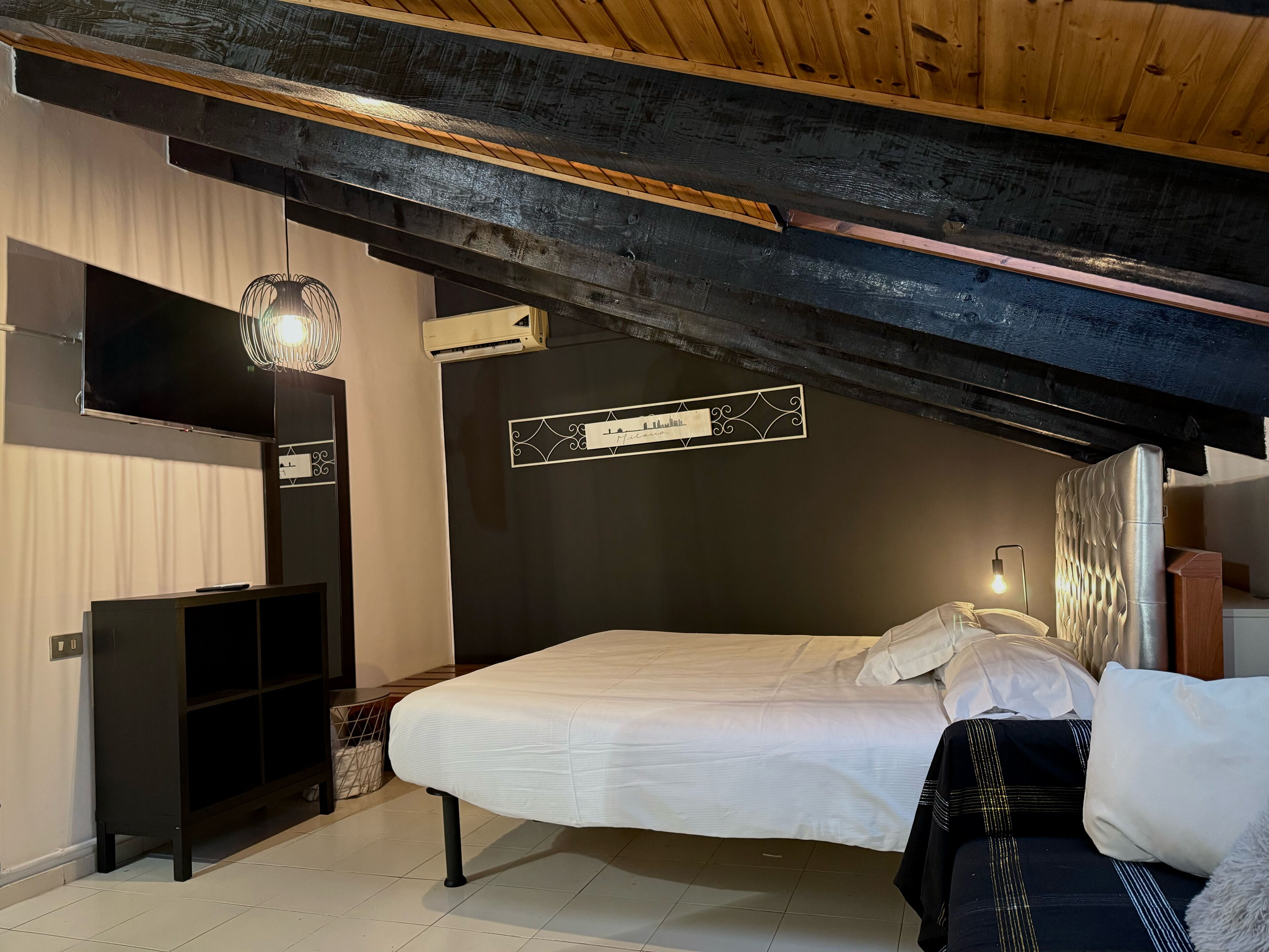 A bedroom with a bed, a TV, a wardrobe, and a nameplate on the wall.