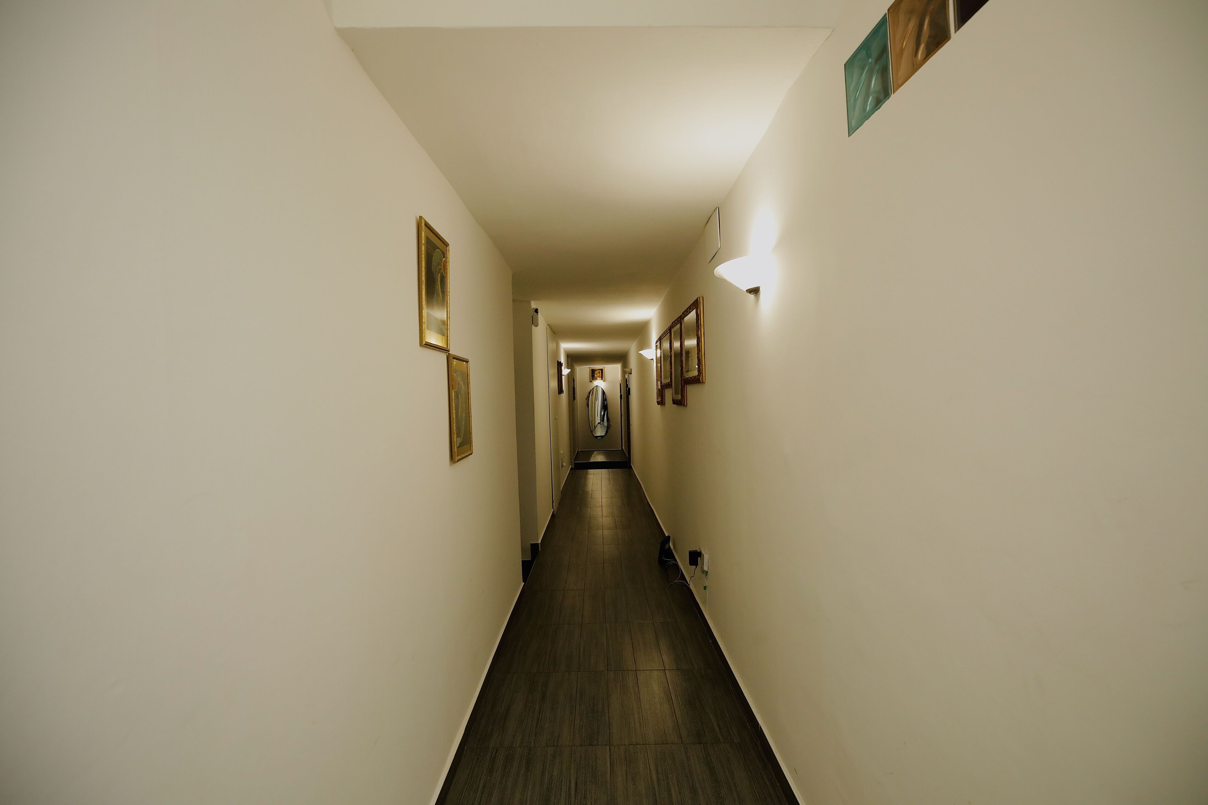A narrow hallway with a wooden floor and white walls.