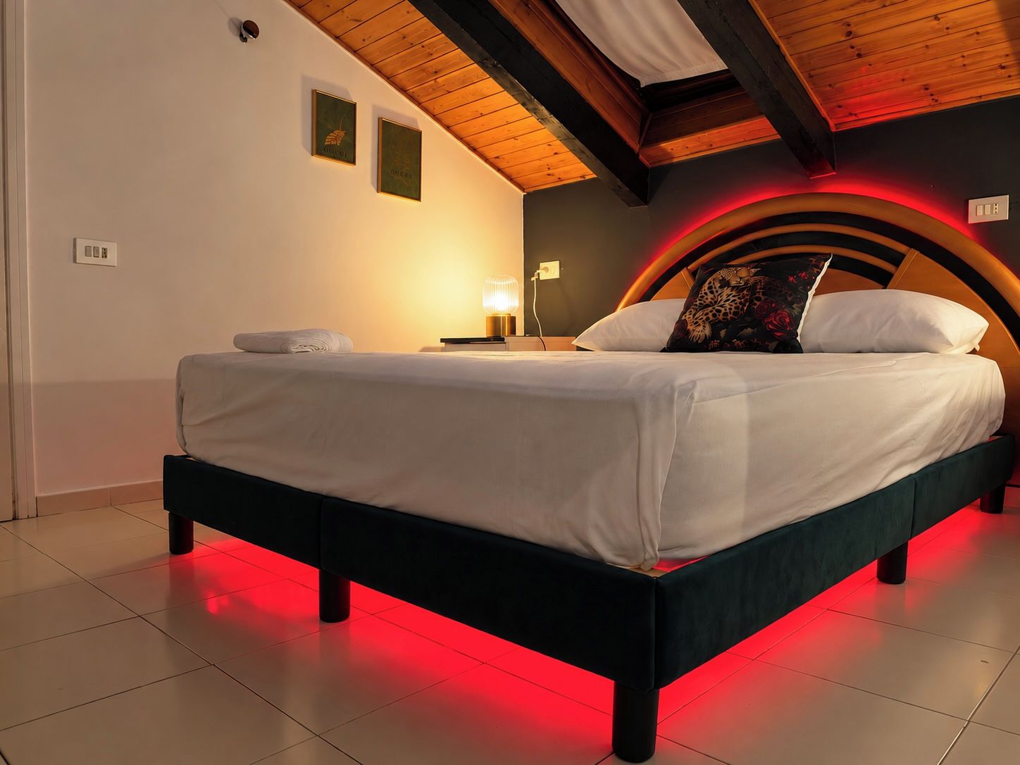 Ein Schlafzimmer mit einem Bett, einem Nachttisch, einer Lampe und einer Wandleuchte.