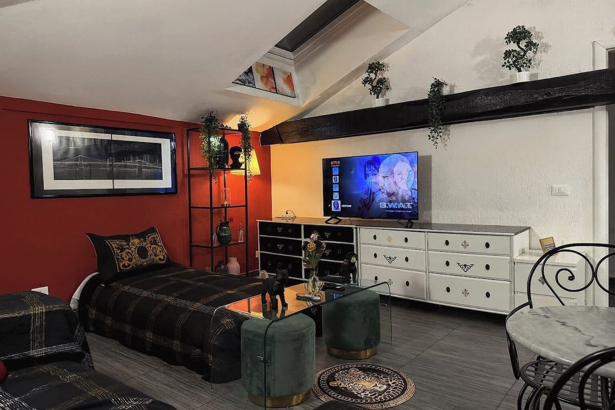 Uma sala moderna com uma cama, uma televisão, um sofá e um espaço de refeições.
