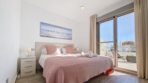 Ein Schlafzimmer mit einem großen Bett, einem Nachttisch, einer Lampe und einem Bild an der Wand.