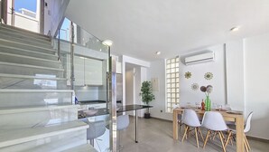 Eine moderne Küche mit einer Glasstiege, einem Essbereich mit Holztisch und -stühlen sowie einem Blumentopf.
