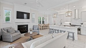 A spacious living room with a fireplace, a dining area, and a kitchen with a large island. - Pool ~ Walk to Beach ~ 2 Balconies (Inlet Beach)