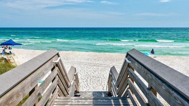 A wooden boardwalk leading to a beach with clear blue water and a few people in the distance. - Pool ~ Walk to Beach ~ 2 Balconies (Inlet Beach)