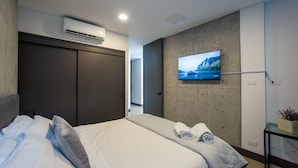Une chambre moderne équipée d’un lit, d’un téléviseur fixé au mur et d’un appareil de climatisation.