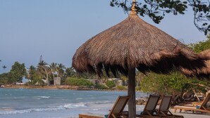 A beach with wooden lounge chairs and a thatched umbrella. - ACASI Rustic Beach (Cartagena)