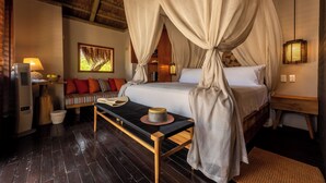 A bedroom with a canopy bed, a sofa, a bedside table, a lamp, and a wall-mounted picture. - ACASI Rustic Beach (Cartagena)