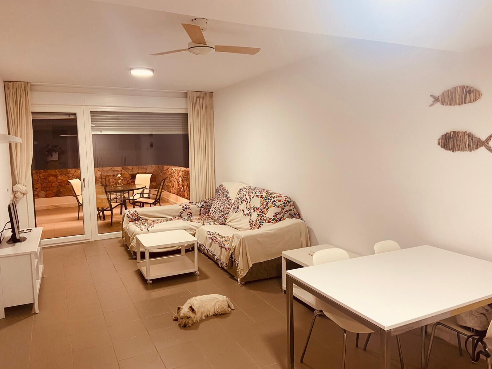 Una sala de estar moderna con un sofá, una mesa de comedor y un ventilador de techo.