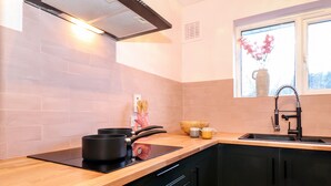 Une cuisine moderne avec un plan de travail noir, des meubles en bois et une fenêtre agrémentée d’un vase de fleurs.