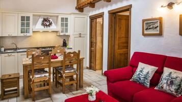 A cozy living room with a red sofa and a dining area with wooden furniture.