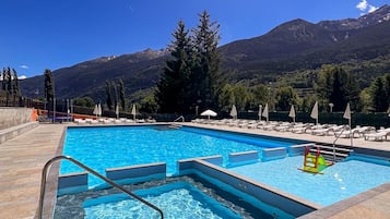 Una piscina al aire libre de temporada, sillones reclinables de piscina
