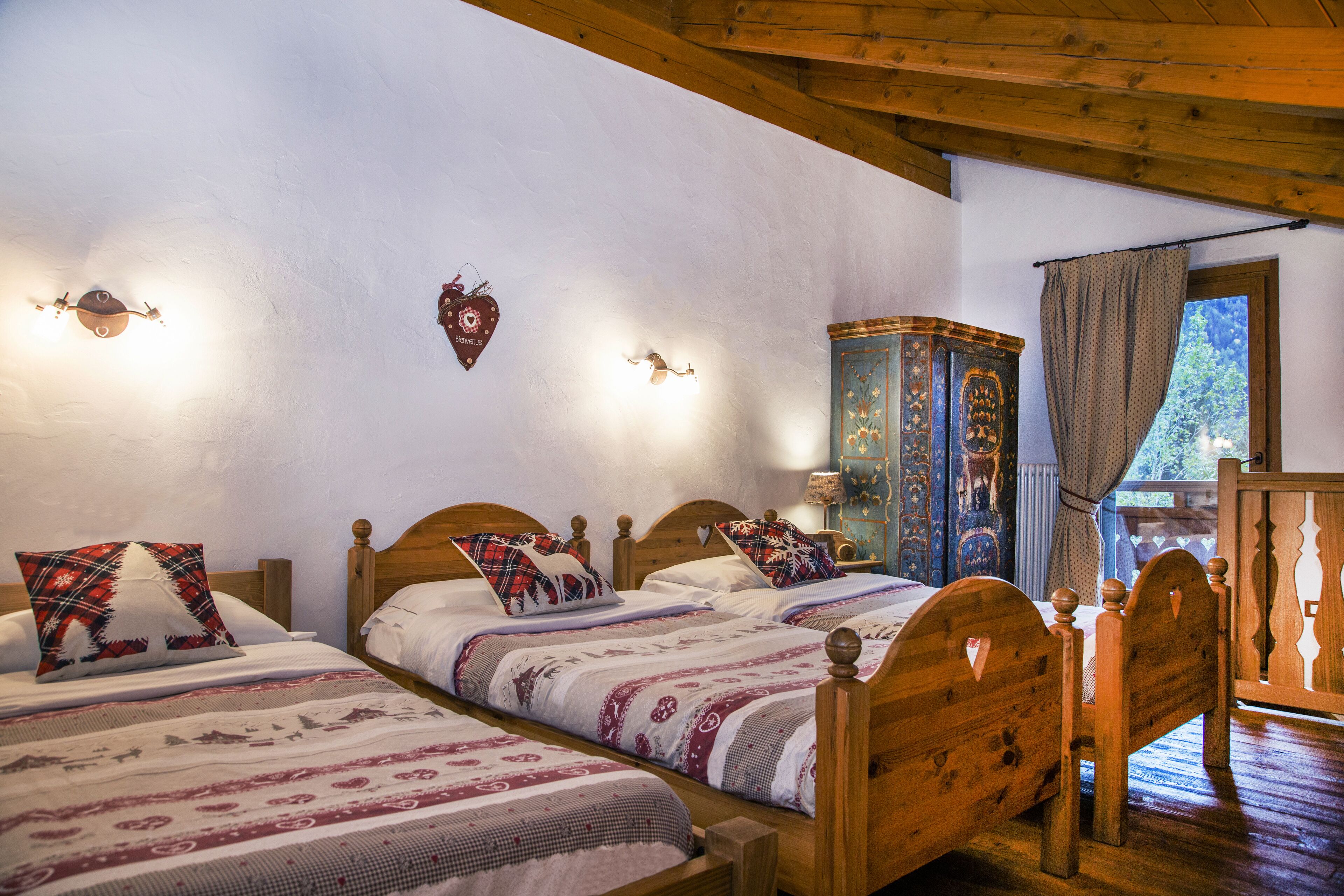 A room with two wooden beds, each with patterned bedding and heart-shaped wall decorations.